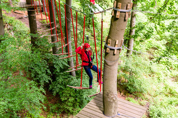 Kind passiert Hängebrücke im Klettergarten