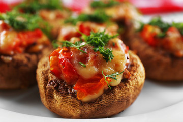 A plate with stuffed mushrooms on wooden background, close-up
