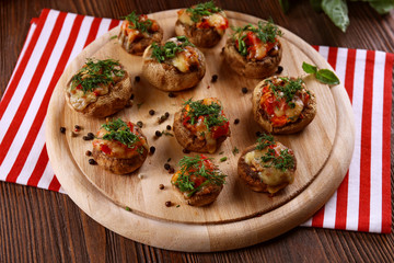 A wooden tablet with stuffed mushrooms on the table