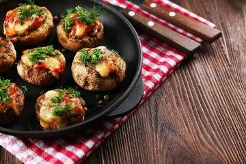 A frying pan with stuffed mushrooms on the table
