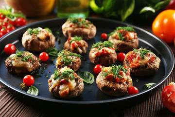 A frying pan with stuffed mushrooms and vegetables on the table