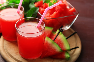 Cold watermelon drinks in glasses, on wooden table background