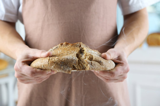 Baker checking freshly baked bread in kitchen of bakery