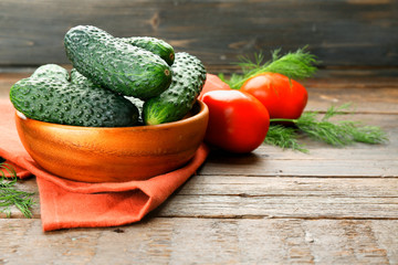 Fresh cucumbers with red cotton serviette and tomatoes on wooden table