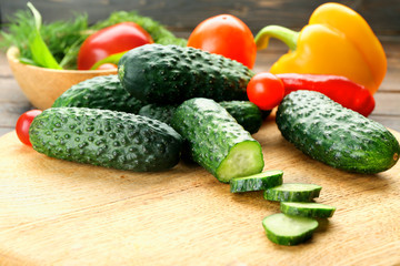 Composition of cucumbers, tomatoes and sweet peppers circles on wooden background