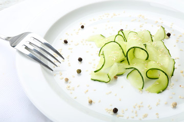 Sliced cucumbers dish on white plate in the restaurant, close up