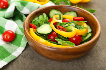 Vegetable salad with cucumbers  on wooden background decorated with green checked cotton serviette and sweet pepper