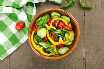 Vegetable salad with cucumbers  on wooden background decorated with green checked cotton serviette and sweet pepper