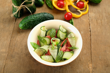 Vegetable salad with cucumbers on wooden background