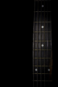 guitar neck isolated on black background, vertical view, low key image