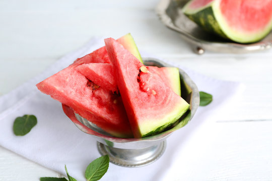 Sliced watermelon in metal bowl on white table