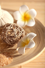 Natural relaxing spa set in a bowl with sea salt on wicker background, close up