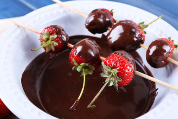 Delicious strawberries in chocolate in a bowl on wooden table