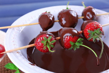 Delicious strawberries in chocolate in a bowl on wooden table
