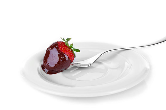 A fork and a strawberry in chocolate isolated on white