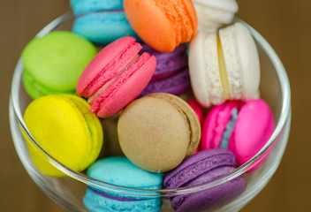 colorful macaroons in glass on wooden table