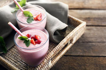 Fresh strawberry yogurt on wicker tray on wooden background