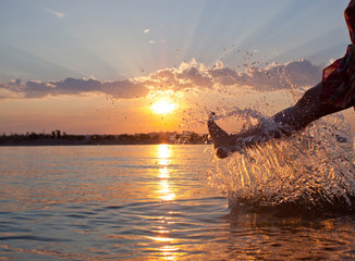 женщина брызгает речной водой в лучах заката