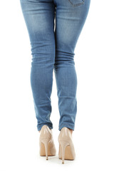 Female legs in beige high-heeled shoes and jeans on white backgr