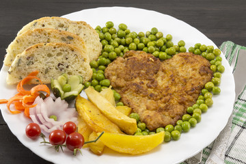 Steak with potatoes, cherry tomatoes and peas on plate