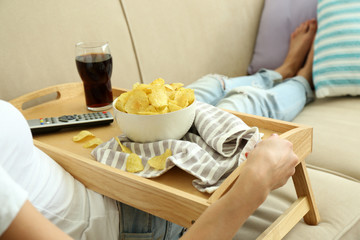 Obraz na płótnie Canvas A girl with a tray having lunch on a sofa, close-up