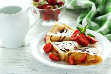 Tasty pancakes with strawberry on white wooden background
