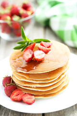 Tasty pancakes with strawberry on grey wooden background