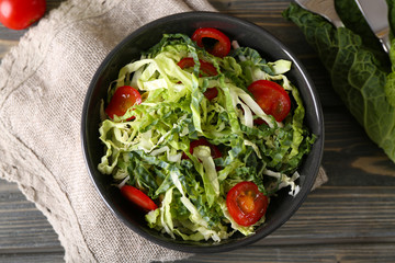 Savoy cabbage and tomato salad served in bowl on wooden table