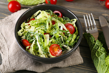 Savoy cabbage and tomato salad served in bowl on wooden table
