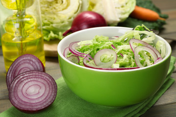 Savoy cabbage and onion salad served in bowl on wooden table