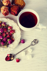 Tea and tea rose flowers on table closeup
