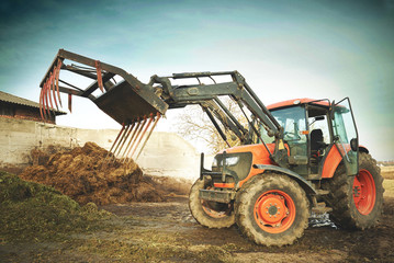 Dirty agricultural tractor with grasper for dung ready to work

