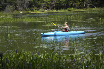 Young woman in kayak on Mud Pond in Sunapee, New Hampshire, horizontal.