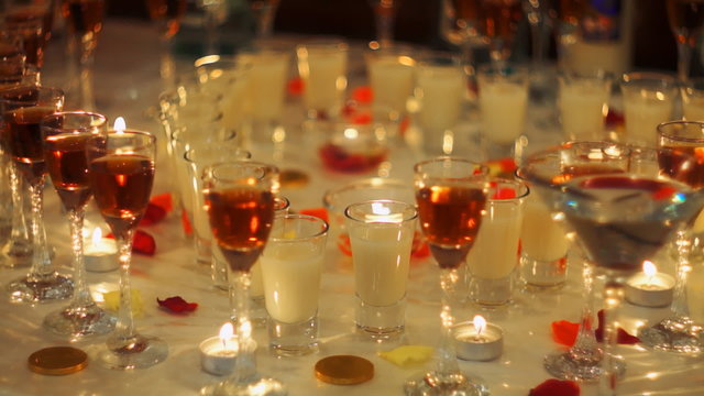 Holiday buffet table with alcohol drinks, decorated with candles and rose petals.