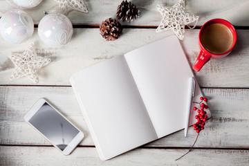 The open notebook on the wooden table with a phone