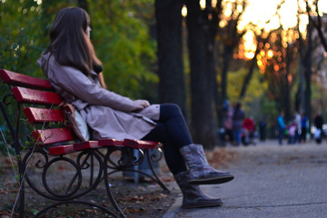 Girl sitting on the bench in park background