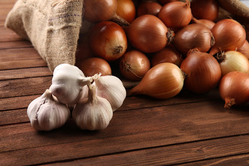 Scattered sac with fresh onions and garlic on wooden background