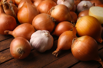 Fresh onions with garlic on wooden background