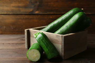 Fresh zucchini in box on wooden background