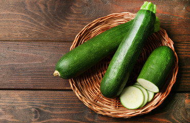 Fresh zucchini on wicker mat on wooden background