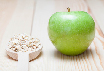 Green apple and oat-flakes in the wooden spoon