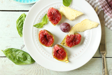 Ripe figs on plate, on color wooden background