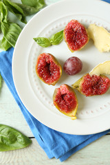 Ripe figs on plate, on color wooden background