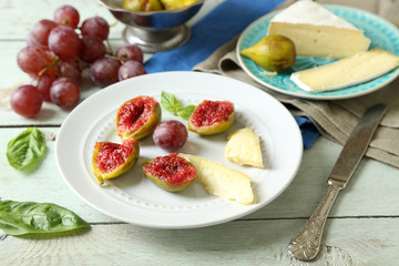 Ripe figs on plate, on color wooden background
