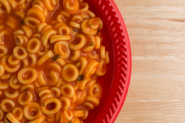 Round spaghetti in a tomato sauce on red plate