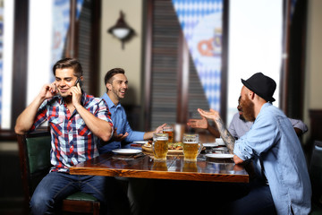 Young men drinking beer and talking in cafe