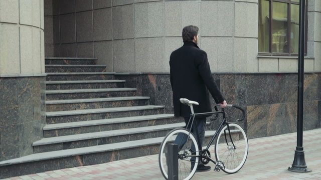 handsome businessman walking with his bicycle in downtown