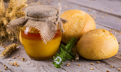 Honey in a jar, slice of bread, wheat and milk on an old vintage