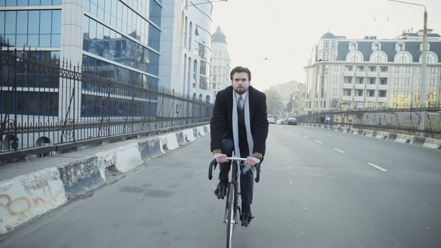 handsome businessman riding a bicycle in downtown slow motion