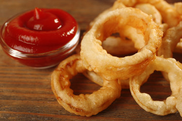 Chips rings with red sauce on wooden background closeup